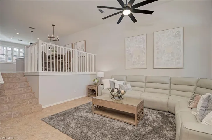 Tiled living room featuring ceiling fan and stairs