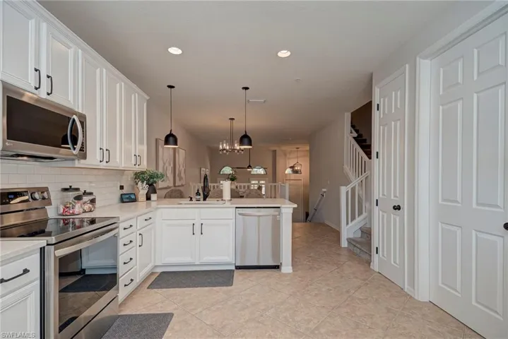 Kitchen with appliances with stainless steel finishes, pendant lighting, a chandelier, white cabinets, and recessed lighting