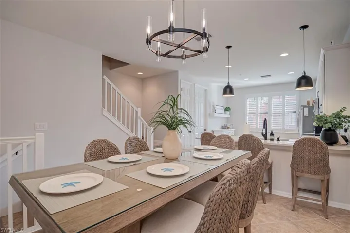 Dining room with light tile patterned floors, a chandelier, recessed lighting, and stairs