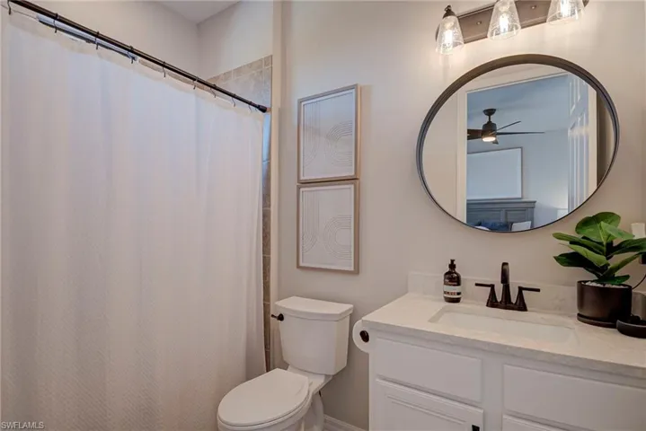 Bathroom featuring a shower with curtain, vanity, and ceiling fan