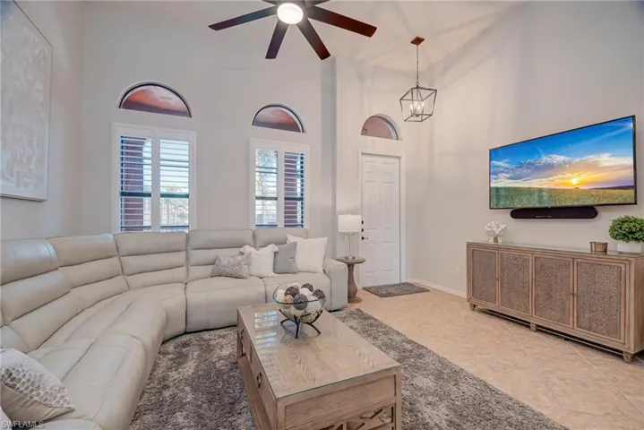 Living room featuring a towering ceiling, tile patterned floors, and a ceiling fan