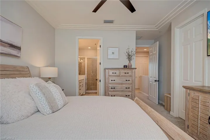 Bedroom with light colored carpet, ceiling fan, connected bathroom, and a closet