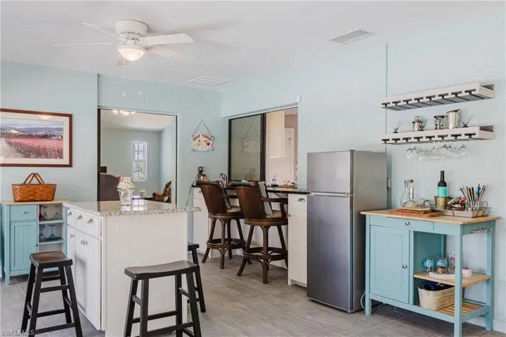 Kitchen with freestanding refrigerator, ceiling fan, blue cabinetry, open shelves, and a kitchen island
