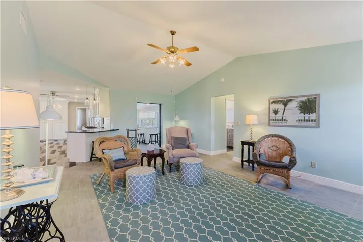 Living room with vaulted ceiling, ceiling fan, and baseboards