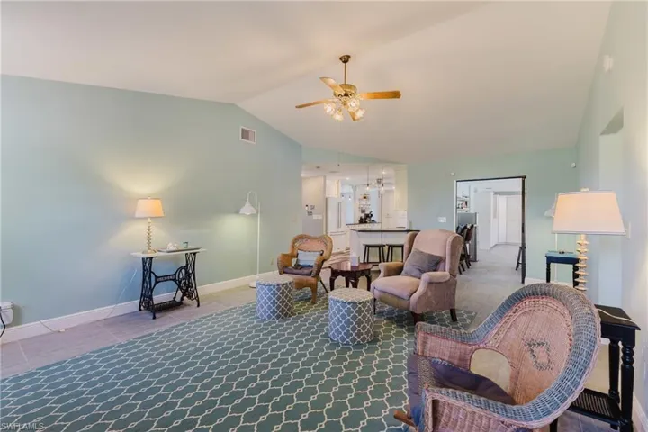 Living room with vaulted ceiling, ceiling fan, and baseboards