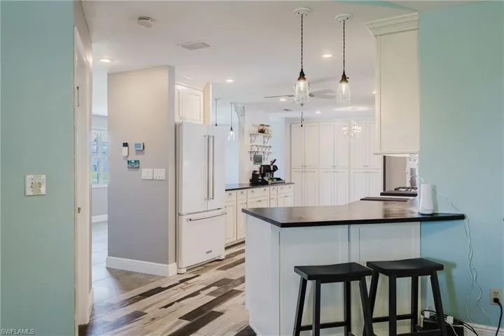Kitchen featuring high end white fridge, dark countertops, white cabinetry, light wood-type flooring, and a peninsula