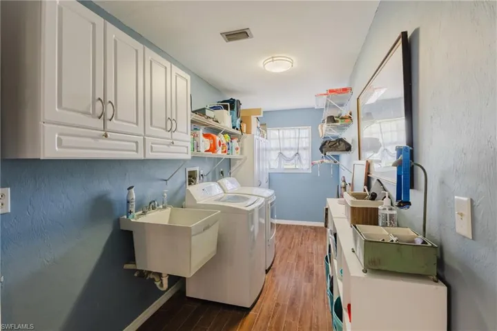 Laundry room featuring washing machine and clothes dryer, cabinet space, wood finished floors, and baseboards