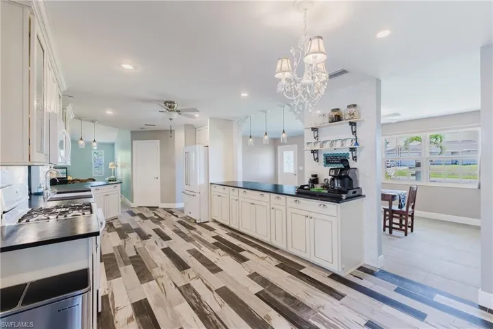 Kitchen with dark countertops, white appliances, ceiling fan, baseboards, and a sink