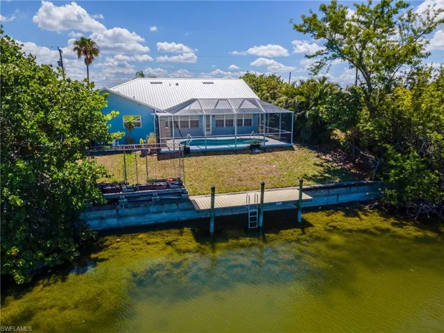 Dock area featuring an outdoor pool, glass enclosure, a yard, and a water view