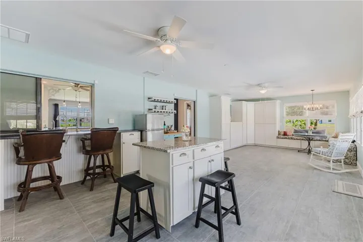 Kitchen featuring healthy amount of natural light, freestanding refrigerator, a ceiling fan, and white cabinets