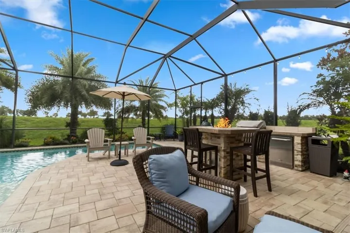 View of patio with a lanai, exterior bar, and area for grilling