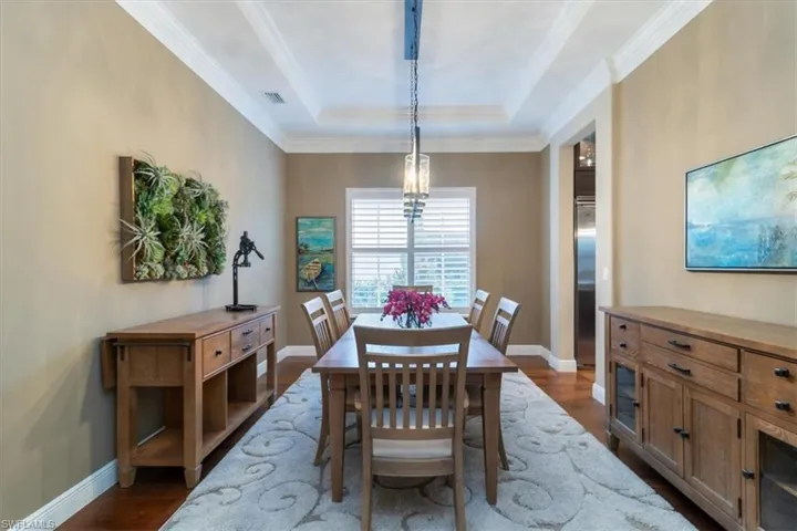 Dining room featuring a tray ceiling, crown molding, and dark hardwood / wood-style floors