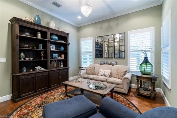 Living room with plenty of natural light, crown molding, a chandelier, and dark hardwood / wood-style floors