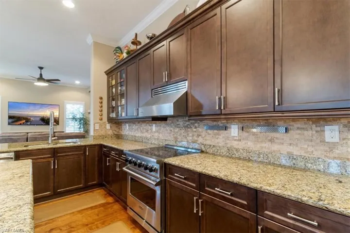 Kitchen with ceiling fan, backsplash, light hardwood / wood-style floors, luxury range, and sink