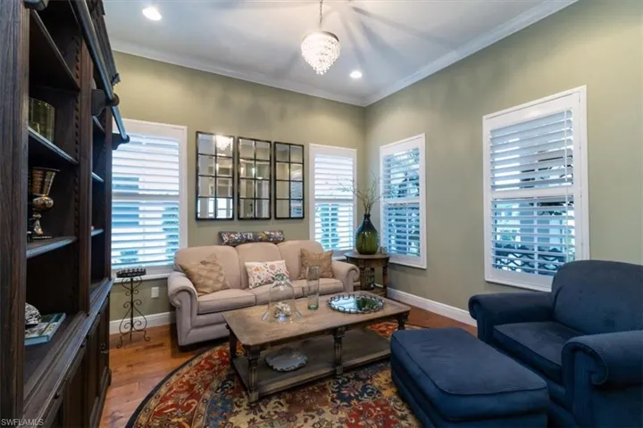 Living room featuring a notable chandelier, crown molding, and hardwood / wood-style floors