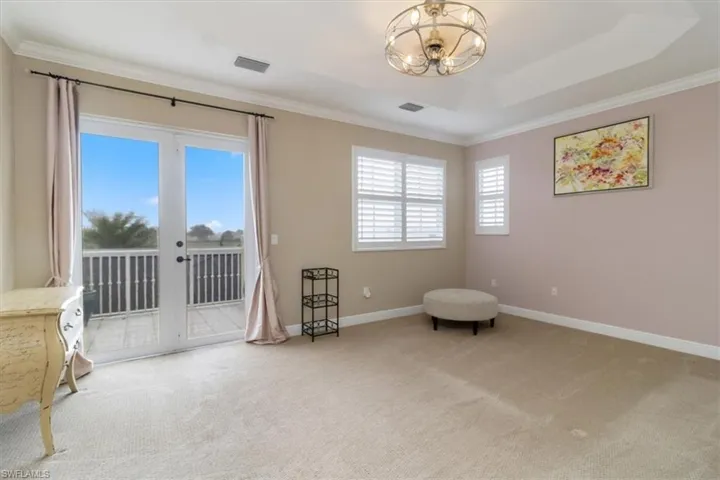 Living area featuring ornamental molding, french doors, light carpet, and a tray ceiling
