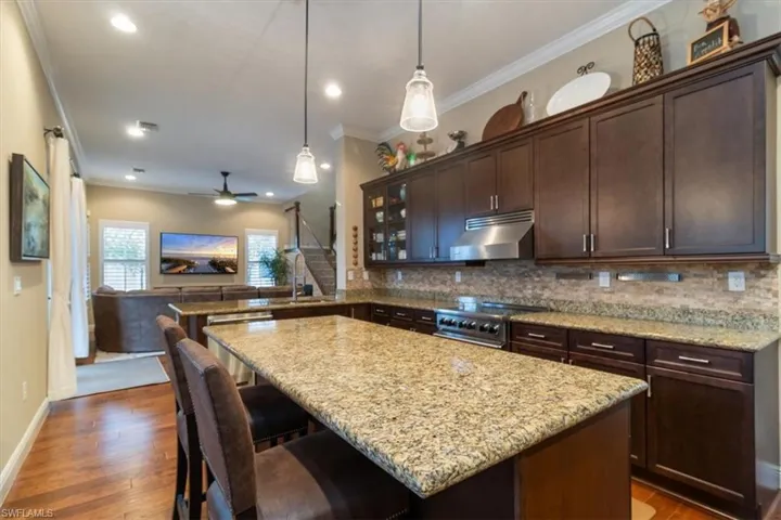 Kitchen with ceiling fan, backsplash, dark brown cabinetry, dark hardwood / wood-style flooring, and stainless steel appliances