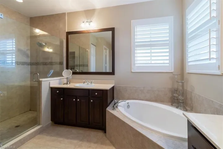 Bathroom featuring tile patterned flooring, separate shower and tub, and vanity