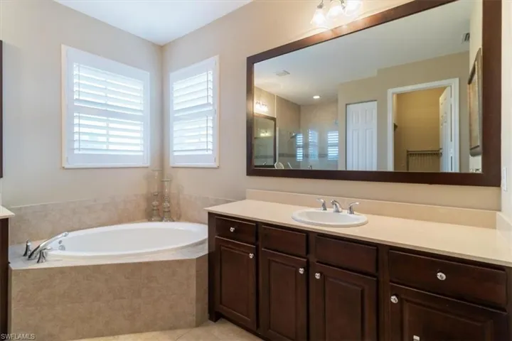 Bathroom featuring plus walk in shower, tile patterned flooring, and vanity