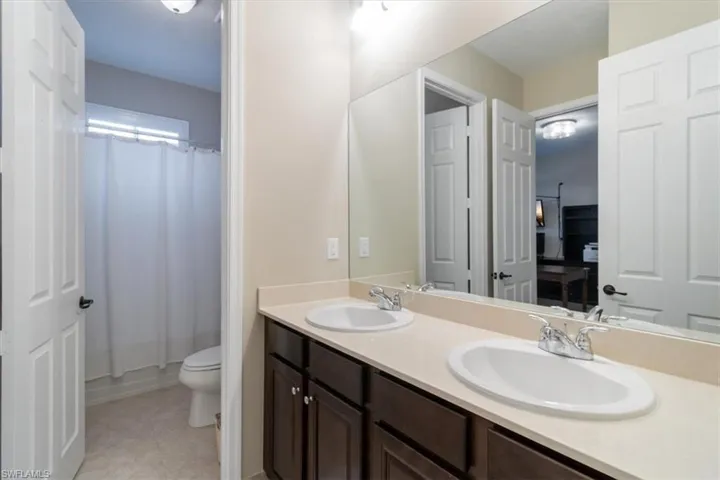 Full bathroom featuring toilet, vanity, shower / bath combo with shower curtain, and tile patterned floors