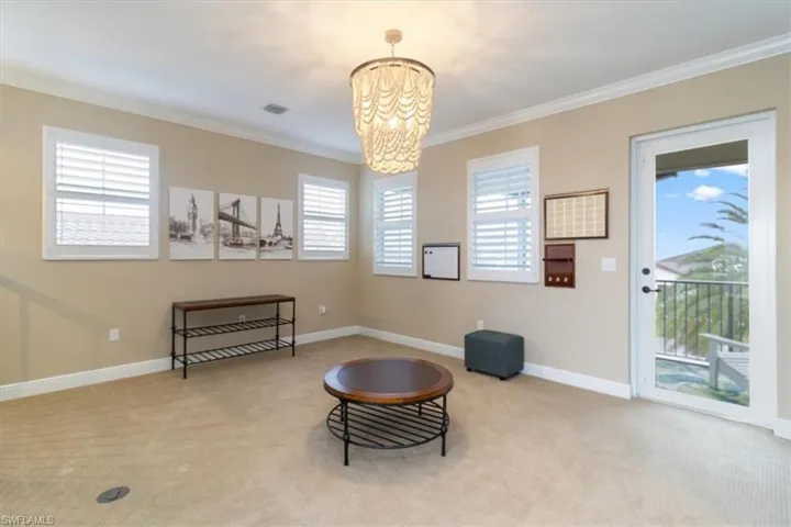 Living area with light carpet, a chandelier, and ornamental molding