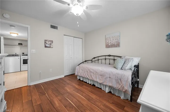Room featuring rich wood-finish flooring, a ceiling fan with integrated lighting, and a white bi-fold closet