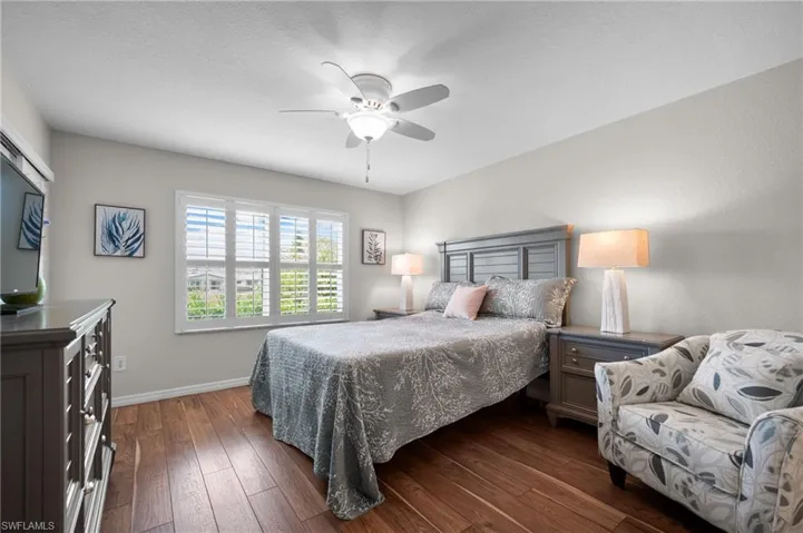 Room featuring rich wood-finish flooring, light gray walls, and a white ceiling fan with integrated lighting