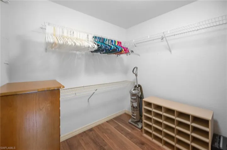 Spacious closet featuring wood-finish flooring, white walls, and built-in wire shelving and hanging rods