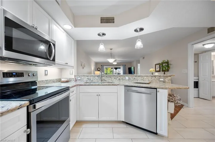 Kitchen featuring white cabinetry, granite countertops, stainless steel appliances, and tile flooring