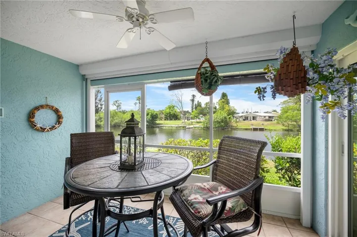 Screened lanai featuring a ceiling fan, textured blue wall, and tiled flooring
