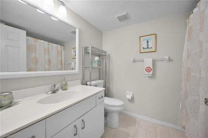 Bathroom featuring a white vanity with integrated sink, chrome faucet, and expansive wall mirror