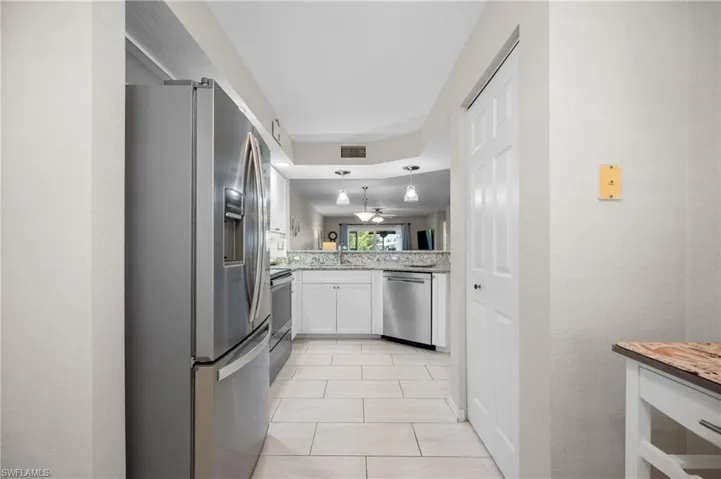 Kitchen featuring stainless steel appliances, white cabinetry, and light-toned countertops