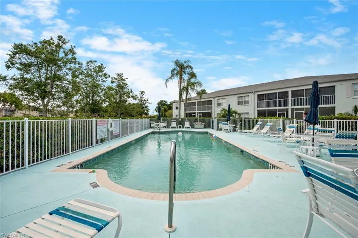 Rectangular swimming pool featuring a curved entry, surrounded by a light blue deck and white fencing