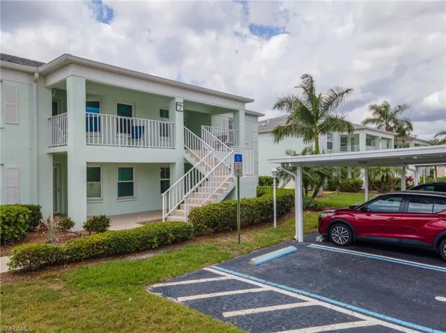 Two-story condominium building featuring a light green exterior, white railings, and an exterior staircase