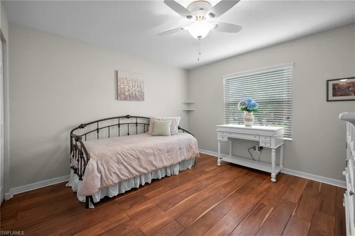 Room featuring wood-finish flooring, a ceiling fan with integrated lighting, a window with horizontal blinds, and neutral wall paint