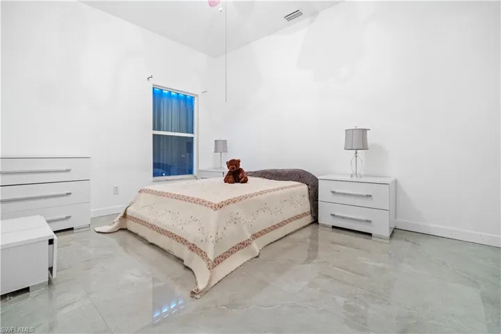 Bedroom with light marble finish floors and vaulted ceiling
