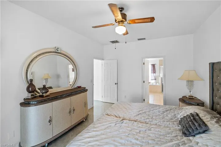 Bedroom featuring light tile patterned floors, a ceiling fan, and ensuite bath