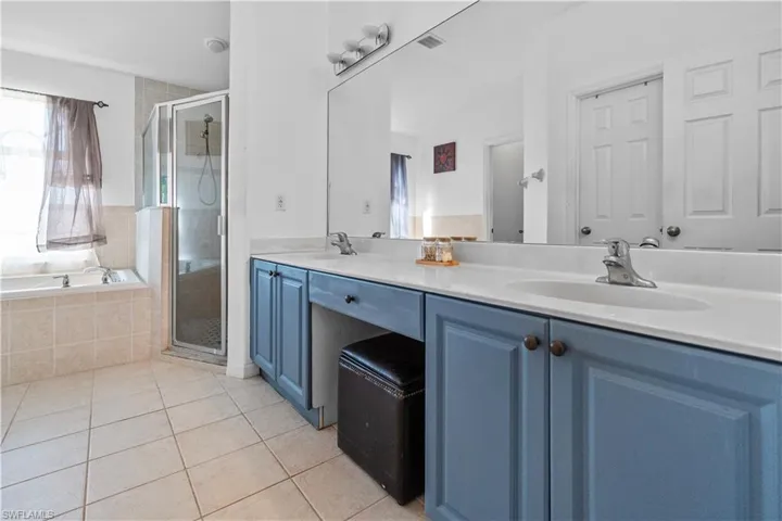 Full bathroom featuring double vanity, a stall shower, light tile patterned flooring, and a garden tub