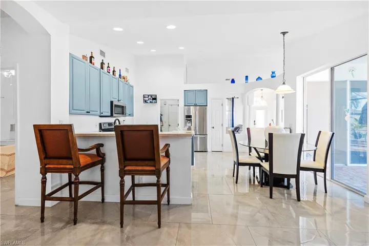 Kitchen featuring arched walkways, a peninsula, blue cabinetry, stainless steel appliances, and a breakfast bar