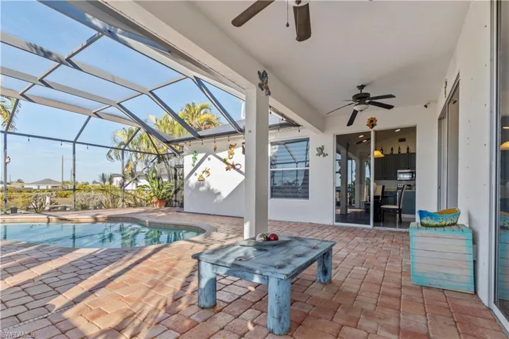 View of patio / terrace with a ceiling fan, glass enclosure, a sunroom, and an outdoor pool