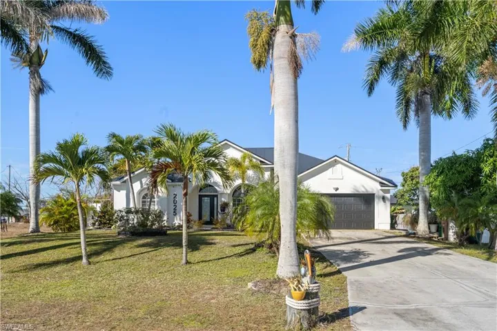 View of front facade featuring driveway, a front lawn, a garage, and stucco siding