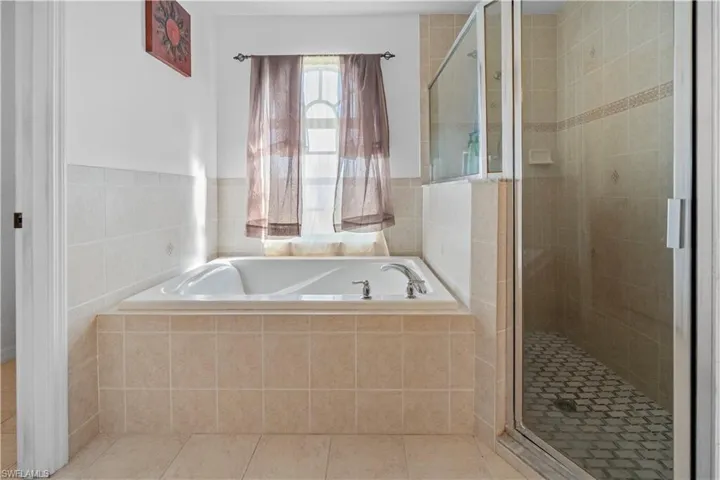 Full bath featuring a shower stall, a bath, and tile patterned flooring