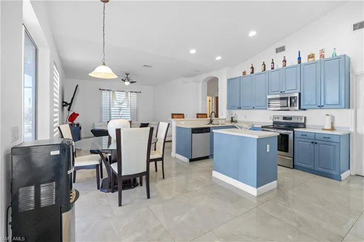 Kitchen featuring lofted ceiling, a peninsula, arched walkways, stainless steel appliances, and light countertops