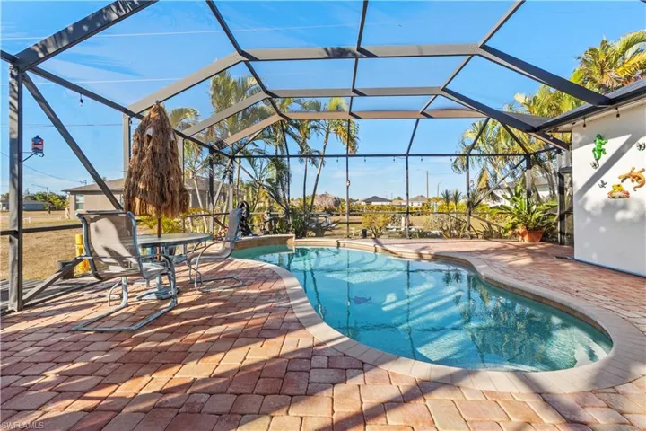 Swimming pool with glass enclosure, a patio area, and a sunroom