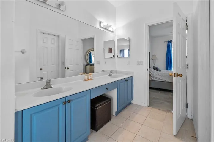 Bathroom with double vanity, ensuite bathroom, and light tile patterned floors