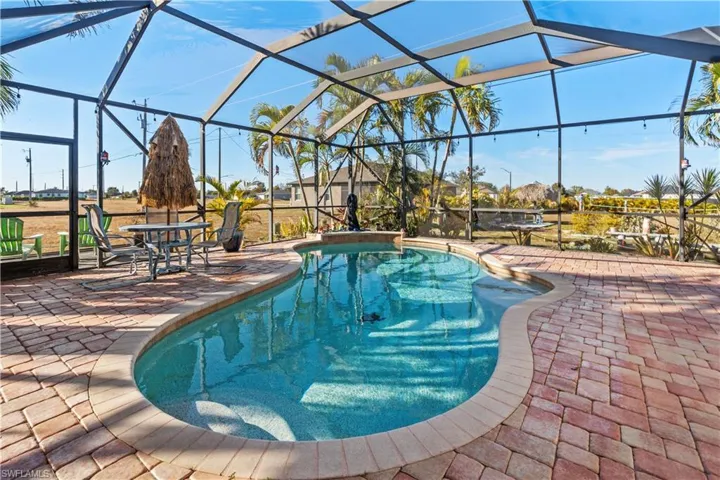 Swimming pool featuring glass enclosure, a patio, and a sunroom