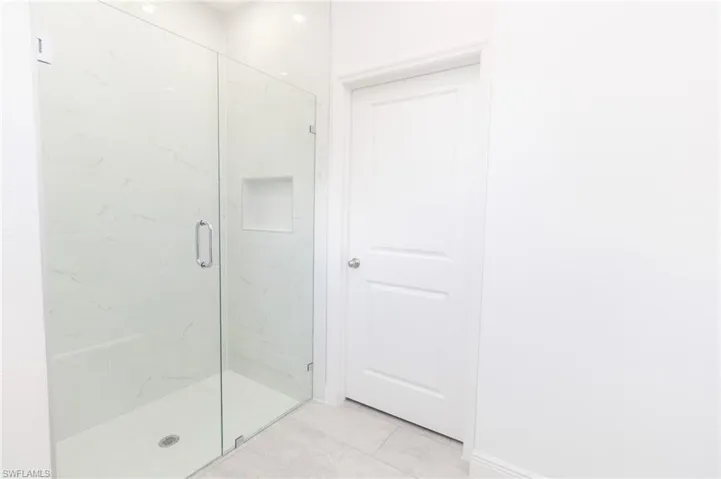 Full bathroom with baseboards, double vanity, a sink, and a shower stall