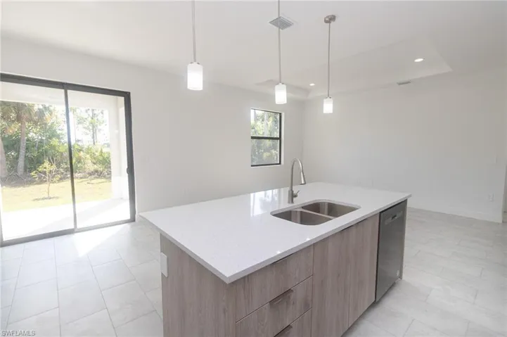 Kitchen with wall chimney range hood, modern cabinets, appliances with stainless steel finishes, and light brown cabinetry