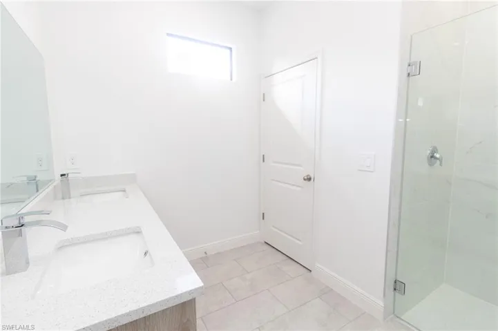 Full bathroom with baseboards, double vanity, a sink, and a shower stall
