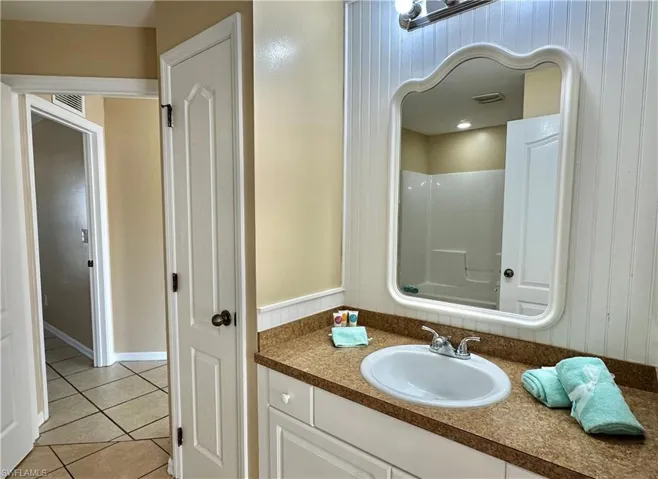 Second Bath J'nJ with Utility Closet, Mirrored Wood Slat Back Wall and Doorway to Third/Front Bedroom and Greatroom